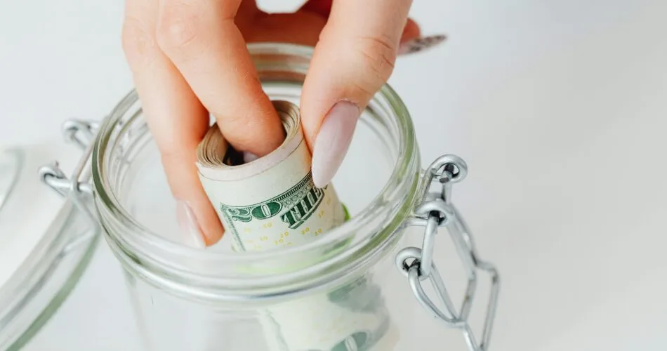 Woman Saving Money in Glass Jar for Emergency Fund
