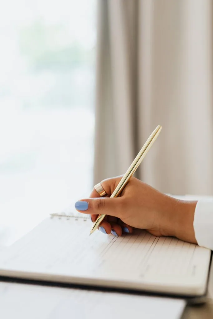 Woman setting goals in her notebook to overcome financial shame